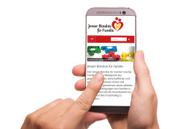 Im Bild ein Smartphone in der Hand einer Person. Auf dem Display sieht man die neue Webseite des Bündnisses für Familie